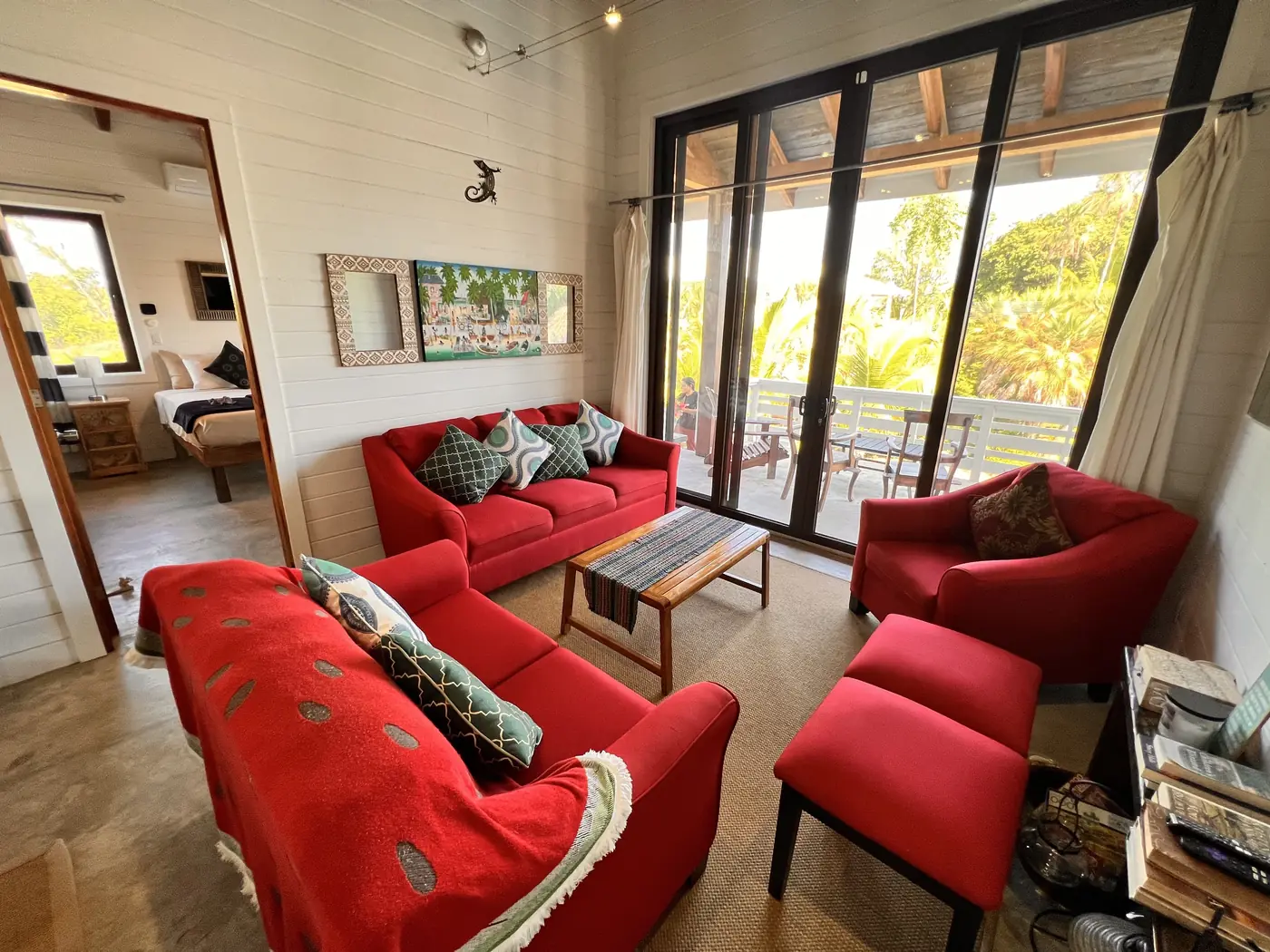Casa living room with red chairs, a sofa, and glass doors to the porch