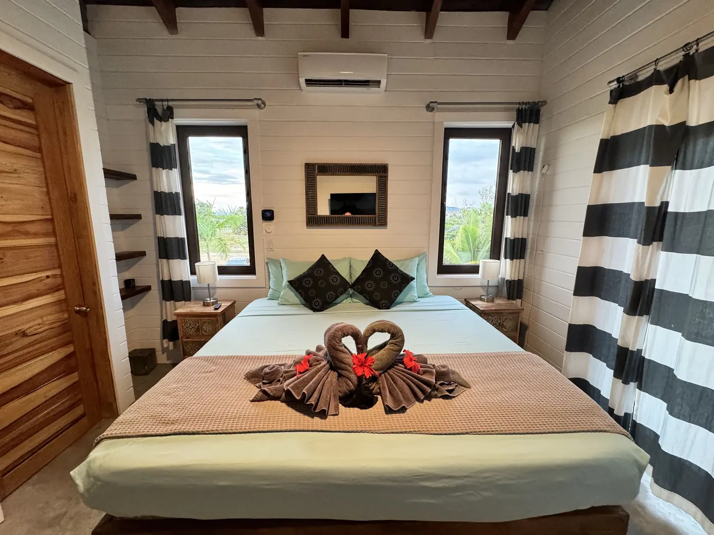 Casa primary bedroom with a made bed and striped curtains