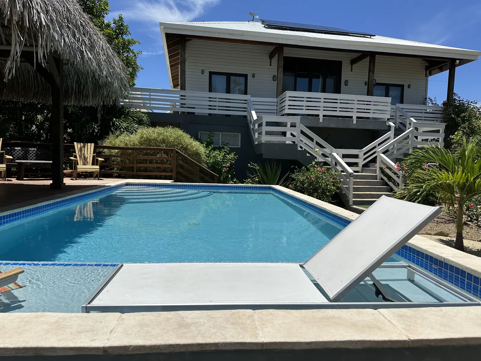 Casa’s pool and the white house behind it, with lounge chairs on the deck