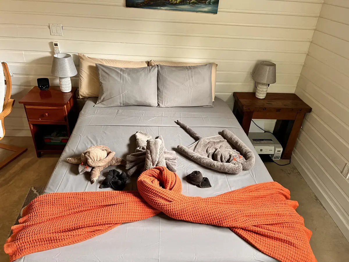 Studio bed with an orange throw and wood nightstands
